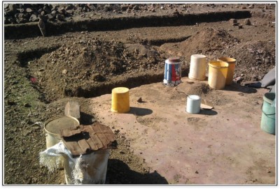 Figure 3. Already-sieved clay stored in buckets or metal containers; in the background are the trenches for the foundation of a building to be constructed; clay process taking place on the floor of a broken down house (photograph taken 2012, by A.C. Nxumalo). 